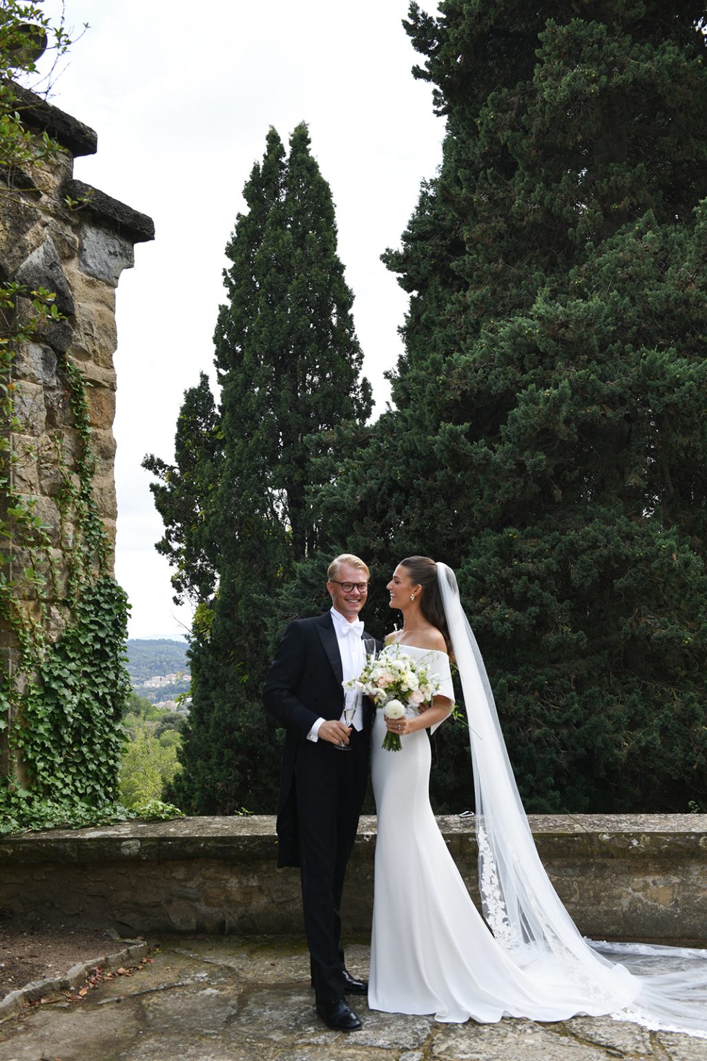 Bride and groom under tall cypress trees at La Baronia, Barcelona